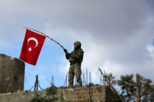 FILE PHOTO: A Turkish soldier waves a flag on Mount Barsaya, northeast of Afrin